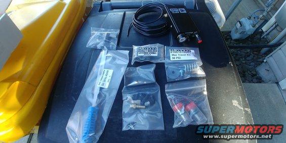 Air suspension kit parts laid out on a dark surface next to a yellow object