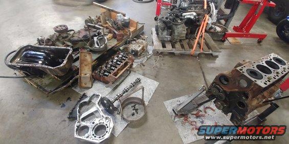 Disassembled engine block and oil pan on a concrete floor