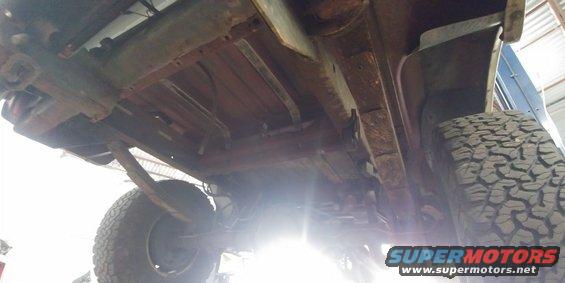 Underside of a rusty vehicle with visible leaf springs and off-road tires
