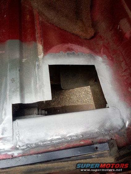 Vehicle floor pan with a cut-out section and body filler applied. Some rust is visible