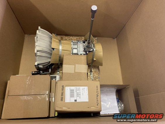 Transmission and various parts packed in cardboard boxes. Shipping label visible on one box