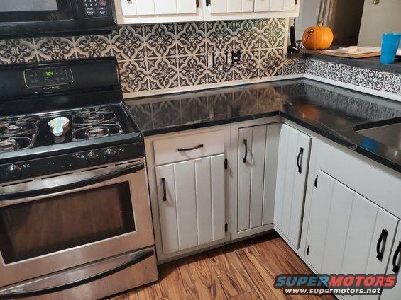 Kitchen counter with black countertop, white cabinets, and stainless steel stove