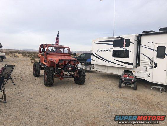 Orange 1992 Jeep Wrangler modified for off-road, parked next to a Sunseeker RV. A small toy Jeep is in front of the RV