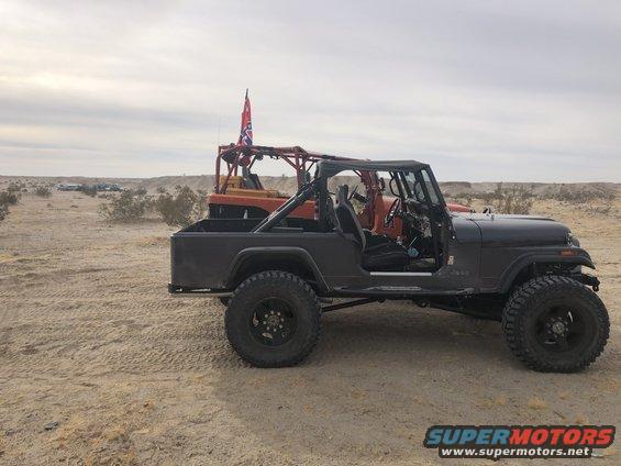 Dark gray Jeep CJ-7, side view, with off-road tires and a Confederate flag visible