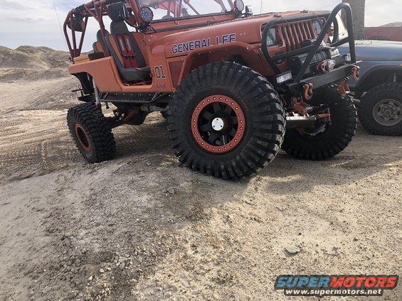 Orange Jeep Wrangler with large tires and roll cage. Text on side says GENERAL LEE 01