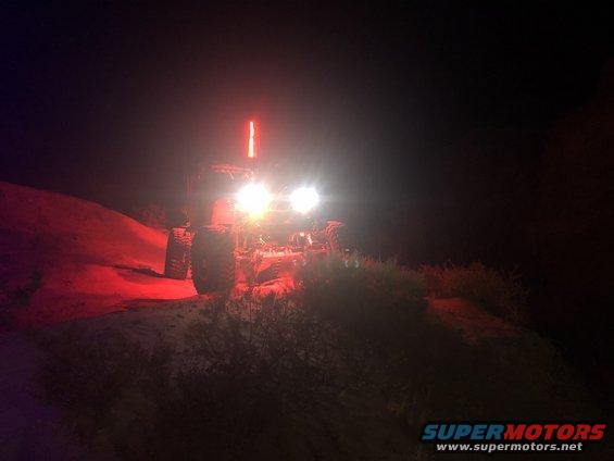 Off-road vehicle with bright headlights and a red light bar at night