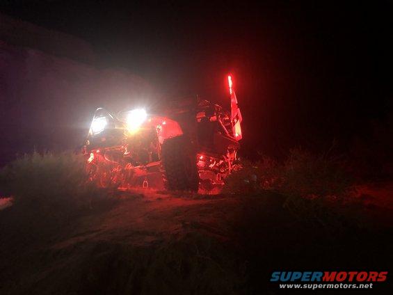 Red off-road vehicle with bright headlights and red taillights at night