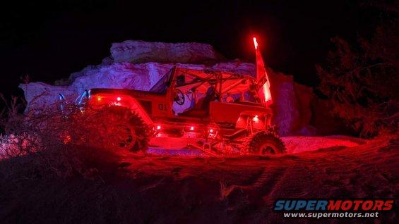 off-road buggy with red and blue lights, and a red flag on top, driving at night