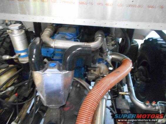 Engine bay showing intercooler, turbocharger, and exhaust piping. Large orange hose is prominent