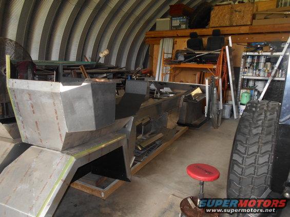 Unfinished vehicle body in workshop, tire visible