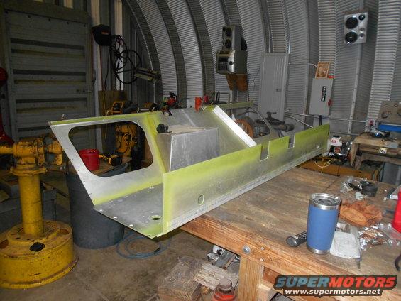 Aluminum boat hull section on a workbench in a garage