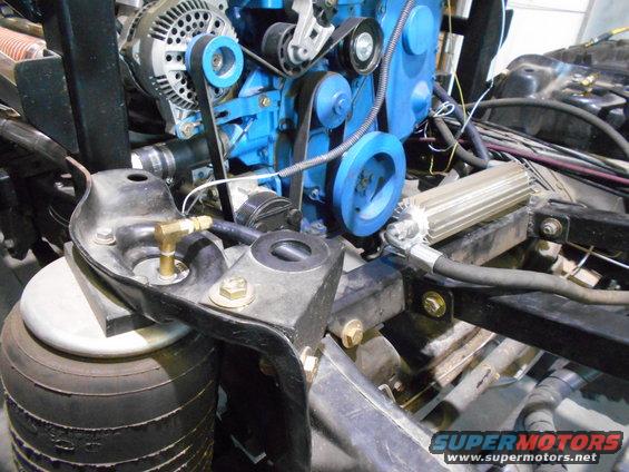 Engine components with blue block, alternator, and belts. Air suspension bag visible