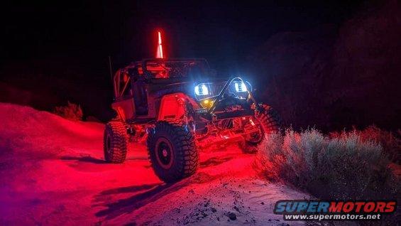 Off-road Jeep with custom lighting, including red underglow and blue headlights, at night