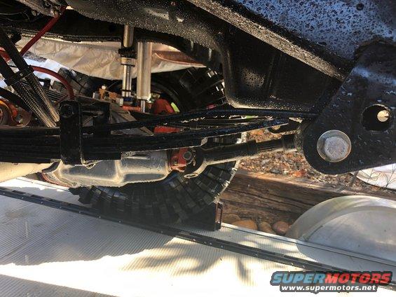 Close-up of vehicle's undercarriage showing leaf springs, driveshaft, and suspension parts