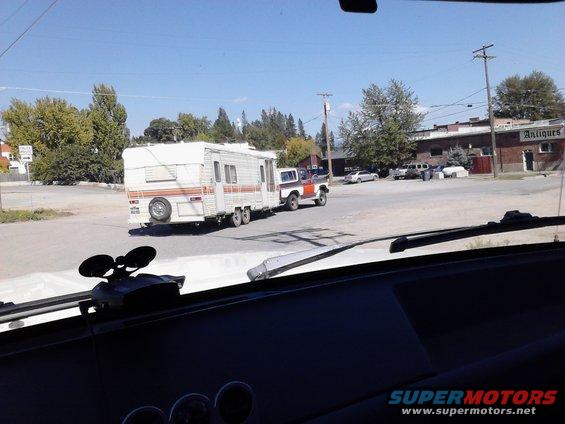 1978 Ford Bronco towing a travel trailer down a street