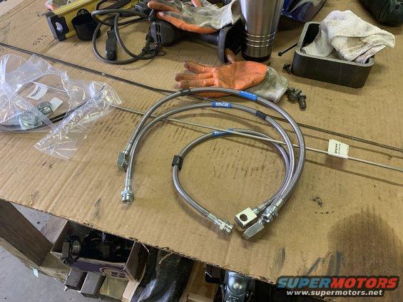 New stainless steel brake lines and various tools on a workbench
