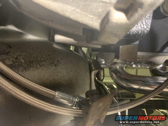 Close-up of exhaust manifold and braided brake line under a vehicle