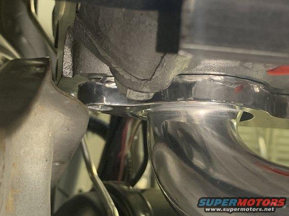 Chrome exhaust pipe connected to a cracked metal manifold
