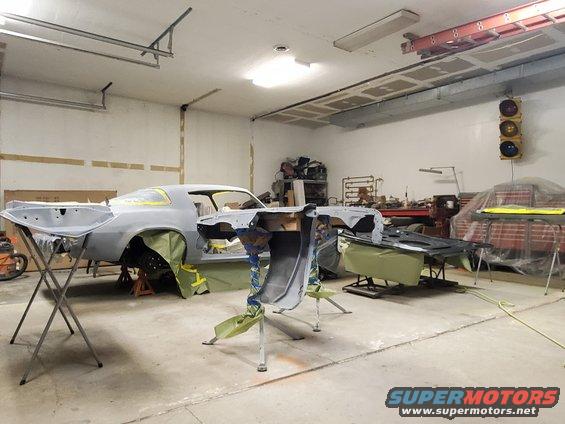 1979 Chevrolet Camaro body in primer on stands in garage, parts laid out