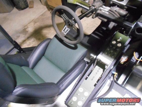Custom interior with bucket seats, aftermarket steering wheel, and a central console with buttons and wiring