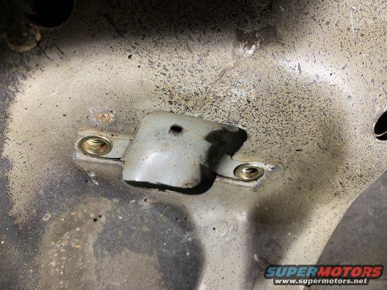 Close-up of a metal bracket with two bolts on a vehicle's undercarriage