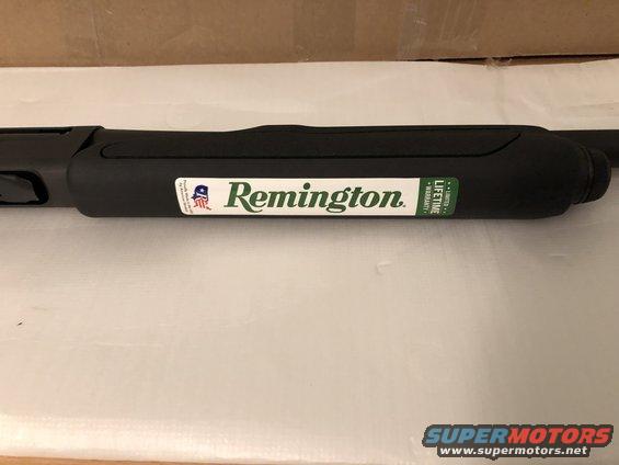 Black Remington shotgun barrel with a white and green logo sticker and a green warranty sticker