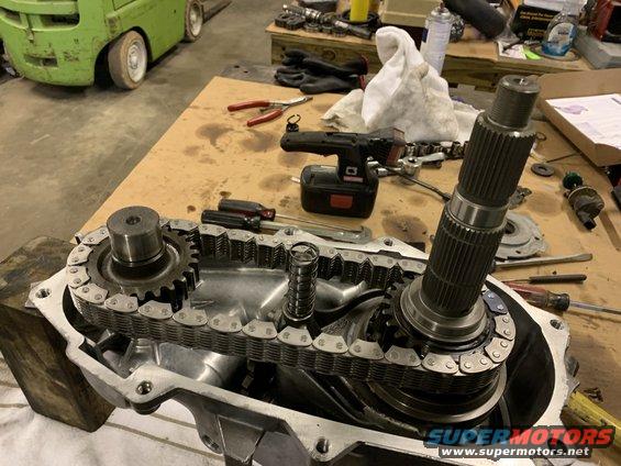 Transfer case assembly with gears and chain, tools on workbench in background