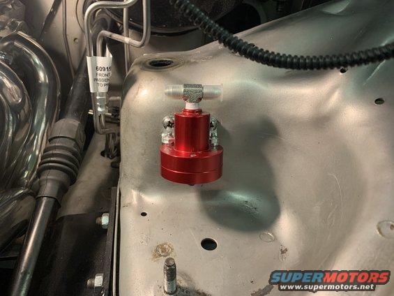 Red aftermarket part mounted on engine bay metal
