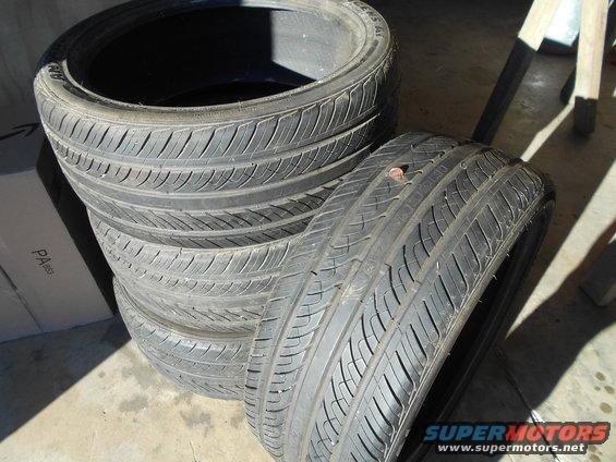 stack of four tires, one with a nail in it