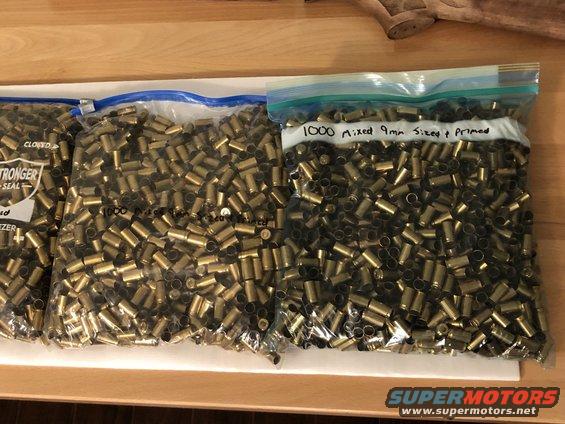 Three bags filled with spent 9mm casings. One bag is labeled '1000 Mixed 9mm Sized + Primed'