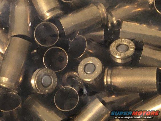 Pile of brass ammunition casings, some with primers visible, others open at the top