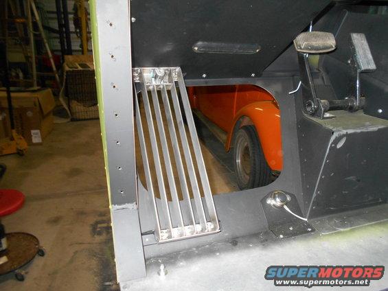 Orange car fender and wheel visible through an opening in a dark interior structure