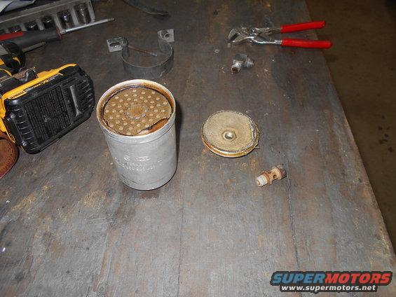Disassembled oil filter housing with tools on a workbench