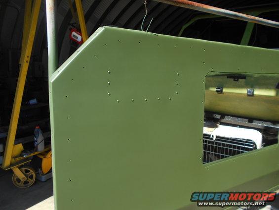 Green vehicle body panel with rivets and a window opening