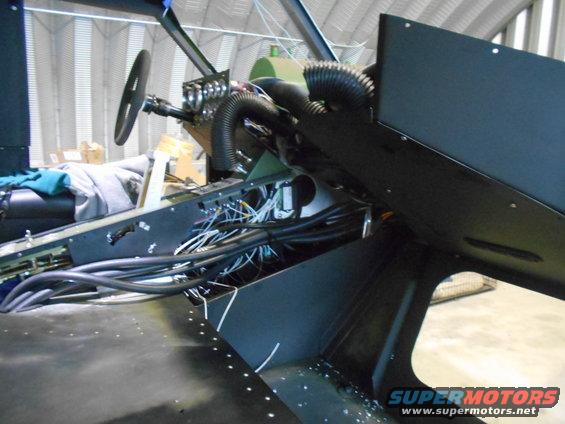 Vehicle interior with steering wheel, lots of wires, and black panels