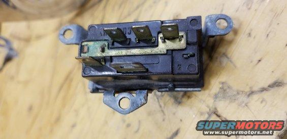 Black electrical relay with metal mounting tabs and brass terminals