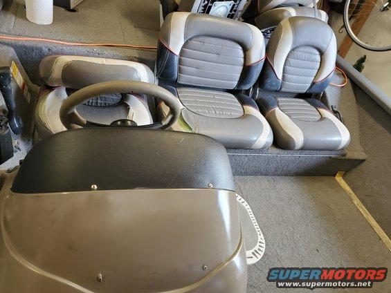 Boat interior with grey and white seats and a steering wheel