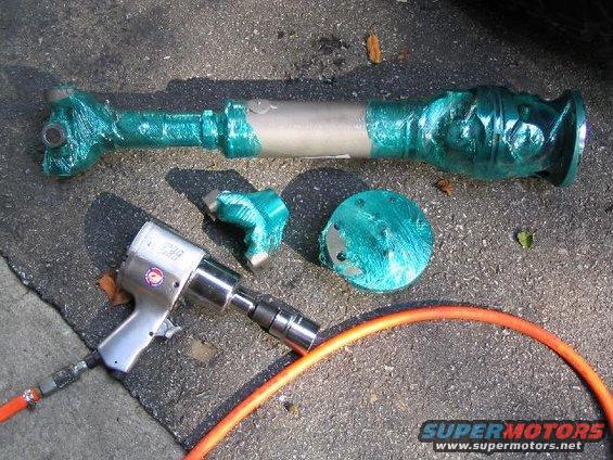 Driveshaft wrapped in green tape next to an impact wrench and air hose