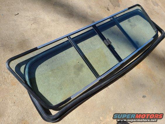 Split rear window assembly with metal frame and rubber seal on concrete