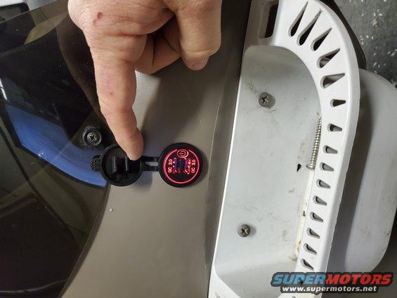Close-up of a dual USB charger with QC 3.0 indicator lights, being touched by a finger