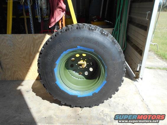 Goodyear tire mounted on a green rim with blue painter's tape around the edge