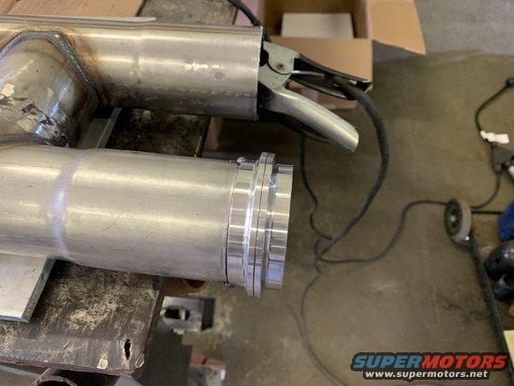Welded exhaust pipe with a flanged connection, clamped by a welding ground