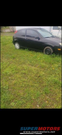 Black hatchback parked on grass, front passenger side visible
