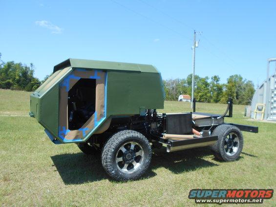 Custom vehicle chassis with green body panels and exposed frame, sitting on grass