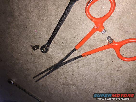 Needle-nose pliers and a wrench on a concrete floor