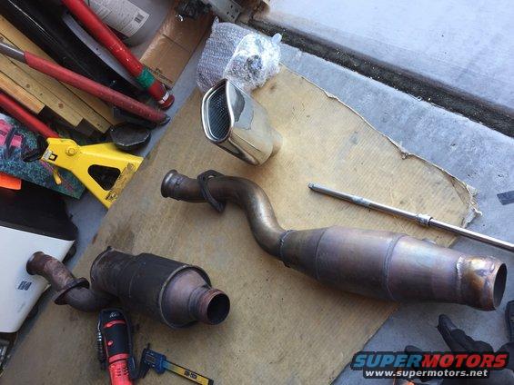 Exhaust system components including a catalytic converter and muffler on a cardboard surface