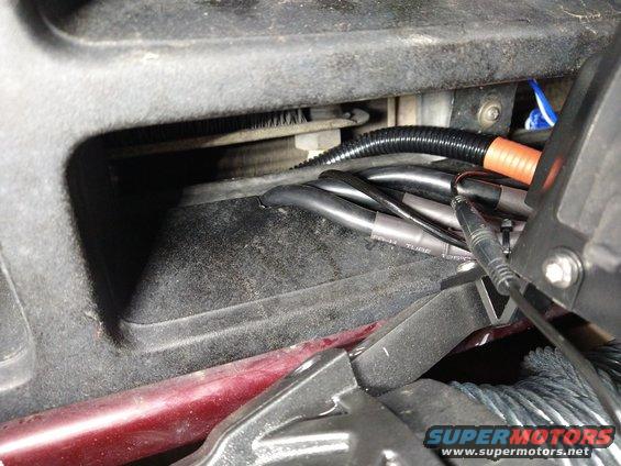 close-up of vehicle wiring and conduit under dash, with some red body panel visible