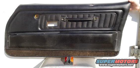 Black vinyl car door panel with horizontal stitching and a chrome pull handle