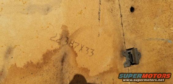 Stenciled numbers 22387X33 on a tan, textured surface with a metal bracket attached