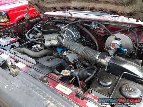 Engine bay with red vehicle in background